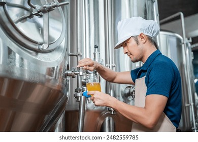 Asian brewer, Craft beer quality is overseen by an experienced brewer wearing an apron in the craft brewery. - Powered by Shutterstock