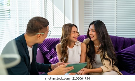 Asian Bridal Shop Owner Using Digital Tablet Help Woman Lesbian Gay Couple Choosing Wedding Gown In Office. Diversity Sexual Equality, Lgbtq Pride, Marriage Equality And Same-sex Marriage Concept.