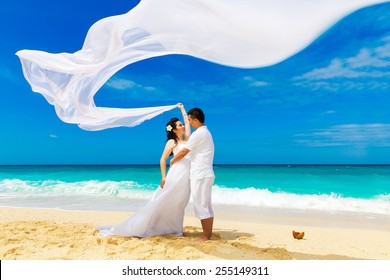Asian bride and groom on a tropical beach. Wedding and honeymoon concept.