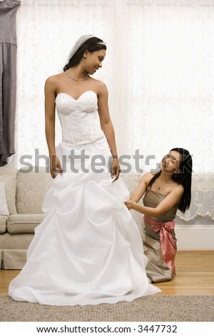 Asian Bridesmaid Fixing African American Brides Dress Stock Photo