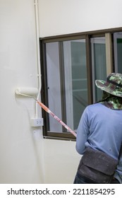 Asian Builder Worker Using Long Handle Roller Brush To Painting Primer White Color On Concrete Wall