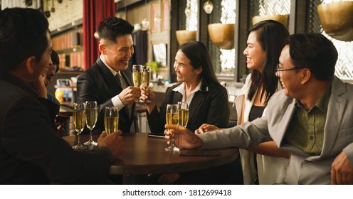 asian business couple toasting and clinking wine or champagne together to celebrate friendship in party with friends in club