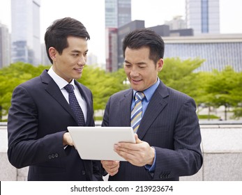 Asian Business Executives Using Ipad In City Park.