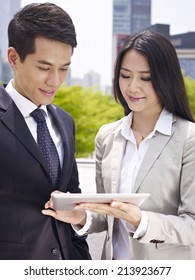 Asian Business Executives Using Ipad In City Park.