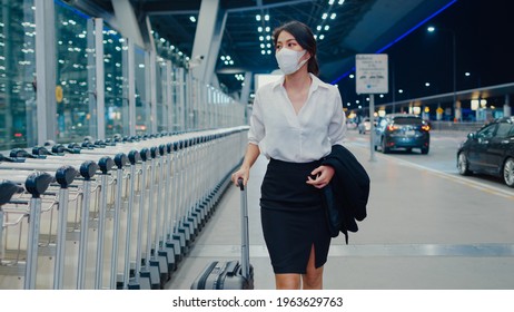 Asian Business Girl Arrive Destination Wear Face Mask With Drag Luggage Walk Outside Wait Car Terminal At Domestic Airport. Business Commuter Covid Pandemic, Business Travel Social Distancing Concept.