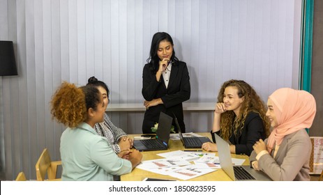 An Asian Business Lady Leading A Meeting With Other Coworkers. Business Women From Different Ethnic Races And Cultures Working Together In An Office For Business Development Or Plan