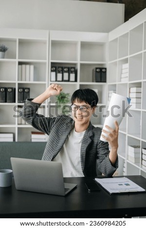 Asian business man are delighted and happy with the work they do on their tablet, laptop and taking notes at the modern office.
