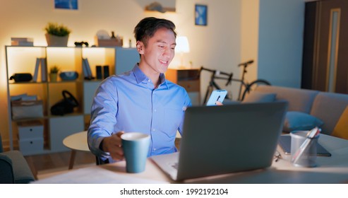 Asian Business Man Drinking Water Or Coffee Is Using Computer And Smartphone To Work In The Evening At Home