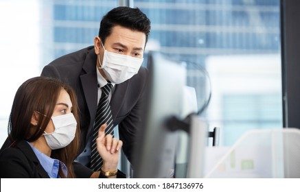 Asian Business Man In Face Mask Discuss With Female Colleague In Office, Startup Project Partner Working Together With Computer, Teamwork Sharng Idea And Brainstorming Concept 