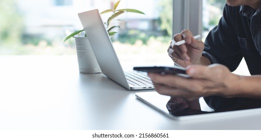 Asian Business Man, Freelancer Working On Laptop Computer, Using Mobile Smart Phone, Online Meeting From Home Office With Digital Tablet On Table, Working At Home, Telecommuting Concept