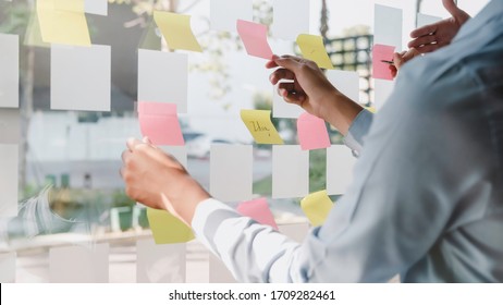 Asian Business Man Hand Holding Note Paper Meeting With New Startup Project Use Post It Notes To Share Idea Discussion And Analysis Data Charts And Graphs.Business Finances And Accounting Concept

