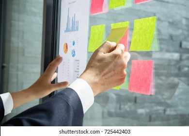 Asian business man hand holding note paper meeting with new startup project use post it notes to share idea discussion and analysis data charts and graphs.Business finances and accounting concept
				