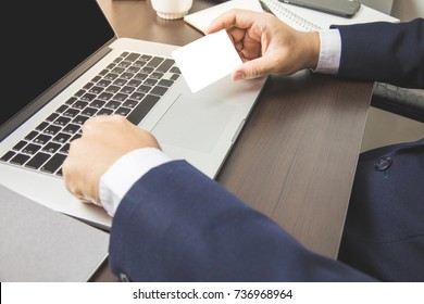 Asian Business Man Holding Card Looking ID Credit For Complete Information Number In Laptop Keyboard On Desk Table Work Space