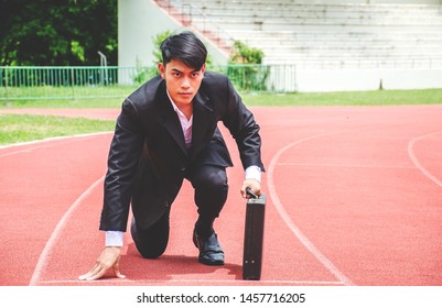 Asian business man kneeling on the starting grid of a running track - Powered by Shutterstock