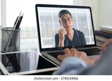 Asian business man making facetime video calling, using zoom online meeting app via laptop computer at home office, teleconference, video conference, work from home, telework, teleconference concept