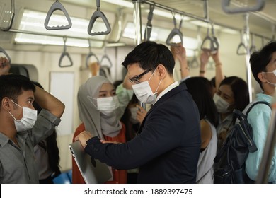 Asian Business Man Passenger Using Smartphone In Train. People In The  Train Wearing Masks And Holding Phone  Travel During Rush Hours. Young Woman Using A Smartphone In The Subway