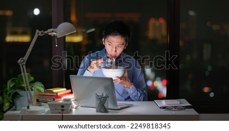 Asian business man staying in office eating instant noodle at night
