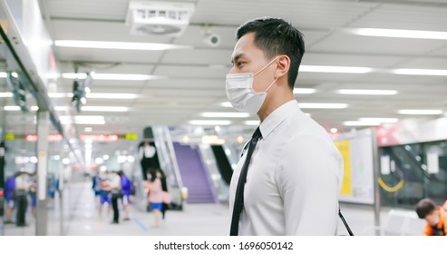 Asian business man with surgical mask face protection and keep social distancing while waiting in the metro or train station - Powered by Shutterstock