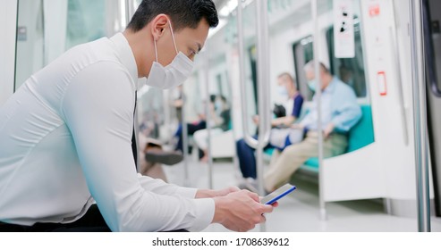 Asian business man with surgical mask face protection use a smartphone and keep social distancing to crowd while commuting in the metro or train - Powered by Shutterstock