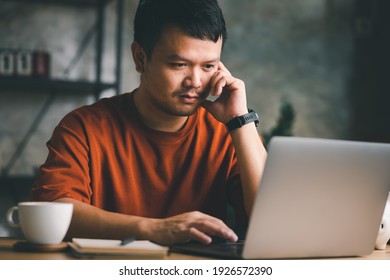 Asian business man thinking while serious working on laptop sitting on desk in modern office at home ,co-working space or at home with copy space, webinar over the internet. - Shutterstock ID 1926572390