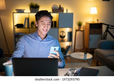 Asian Business Man Use Computer And Smartphone To Work In The Evening At Home