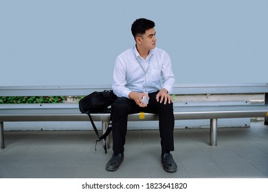 Asian business man waiting for public transportation at bus stop.