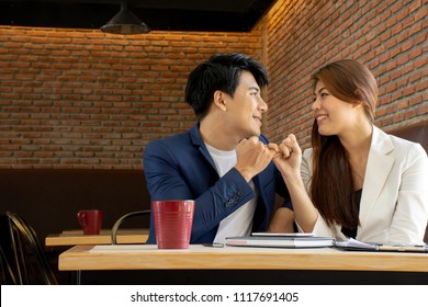 Asian Business Man And Asian Business Woman Look At Each Other And Pinky Swear With Copy Space On Left Side