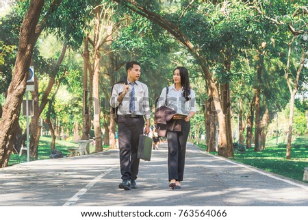 Asian business man and woman walking and talking business in the park, Business talk and relaxing outside concept