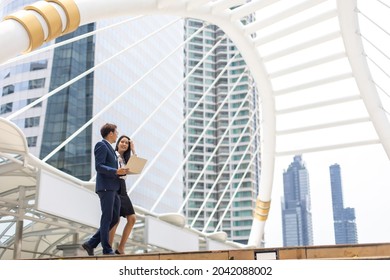 Asian Business Man And Woman Working On Laptop Computer Standing Outside Office Building.