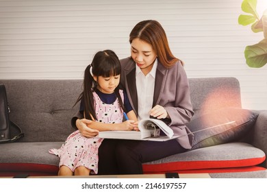 Asian Business Mom Sits With Her Young Daughter Writing Something In Her Mother's Folder After Coming Home From The Office : Mother Paid Attention To Her Daughter's Education While At Home.