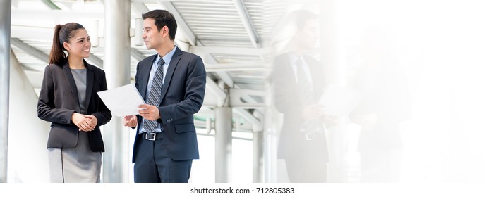 Asian business people discussing document while walking outdoors - panoramic banner with copy space - Powered by Shutterstock