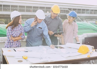 Asian Business People Group Gesturing And Discussion On Meeting And Presentation In Construction Site With Construction Engineer Architect And Worker Looking Building Model And Success Blueprint Plan 