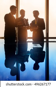 Asian business people having conversation in front of window in conference room, filtered image