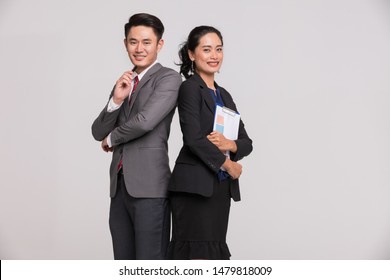 Asian Business People Standing Back To Back, Man Hold Pen And Woman Has Report In Her Hands Isolated On White Background.