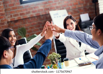 Asian Business People Standing In Office And Giving High Five During Teambuilding.