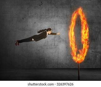 Asian business person flying through ring of fire. Business risk conceptual
