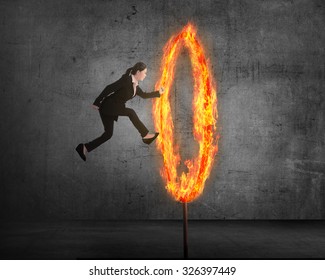 Asian business person jumping through ring of fire. Business risk conceptual