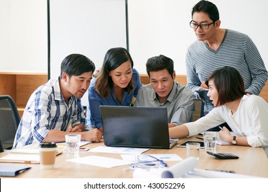 Asian Business Team Discussing Information On Laptop Screen