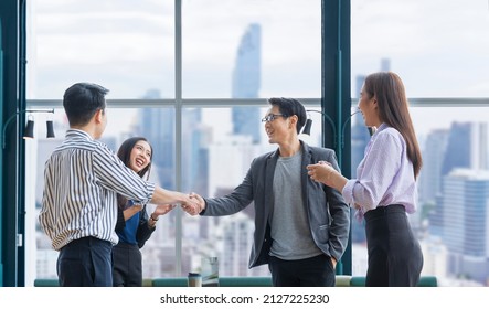 Asian business team leader congratulate his teammate employee for the outstanding achievement team performance by shaking hand in the modern office workplace with skyscraper view