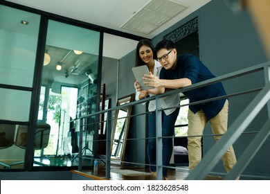 Asian Business Use Laptop Computers And Tablet To Work And Study Online In At Home Office. Two Asia Business Talking To Personal Banker At Their Home