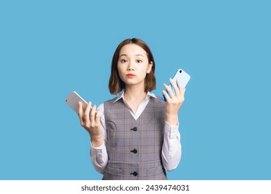 Asian business woman comparing two smartphones.