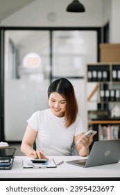 Asian business woman are delighted and happy with the work they do on their tablet, laptop and taking notes at the office. - Shutterstock ID 2395423697
