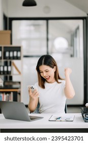 Asian business woman are delighted and happy with the work they do on their tablet, laptop and taking notes at the office. - Shutterstock ID 2395423701
