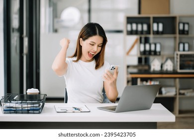 Asian business woman are delighted and happy with the work they do on their tablet, laptop and taking notes at the office. - Shutterstock ID 2395423705