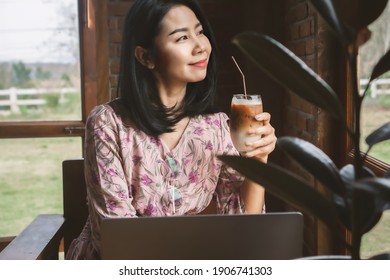 Asian Business Woman Drinking Coffee And Working On Computer Laptop At Cafe Shop,  Work From Anywhere Concept 