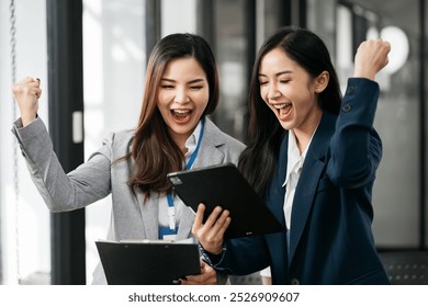 Asian business woman are excited business success with inspiration from their excellent financial results that are happy working in a modern office on a computer. - Powered by Shutterstock