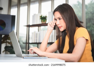 Asian Business Woman Feeling Stressed While He Looks At Unsuccessful Earning From A Computer Note Book, At Workplace, To People And Business Loss Concept.