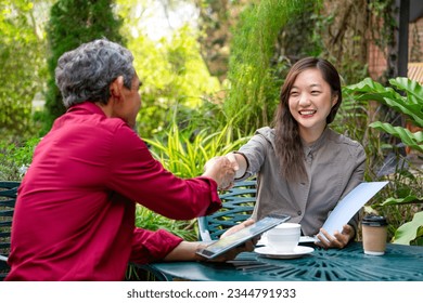 asian business woman handshaking to businessman while discuss work at outdoors coffee shop,concept casual business,casual work,outdoors work,outdoor workspace,digital nomad - Powered by Shutterstock