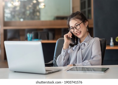 Asian Business Woman Have The Joy Of Talking On The Phone, Laptop And Tablet On The Office Desk.