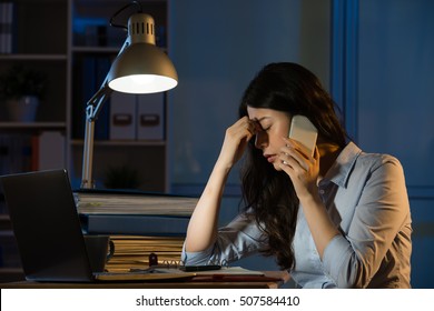 Asian Business Woman Headache On Smartphone Working Overtime Late Night. Indoors Office Background